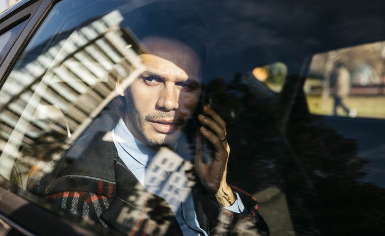 Man sitting on back seat of a car talking on cell phone