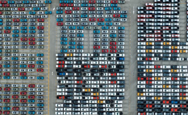 Aerial view of new cars stock at factory parking lot. Above view Aerial view of new cars stock at factory parking lot. Above view cars parked in a row. Automotive industry. Logistics business. Import or export new cars at warehouse. Big parking lot at port terminal